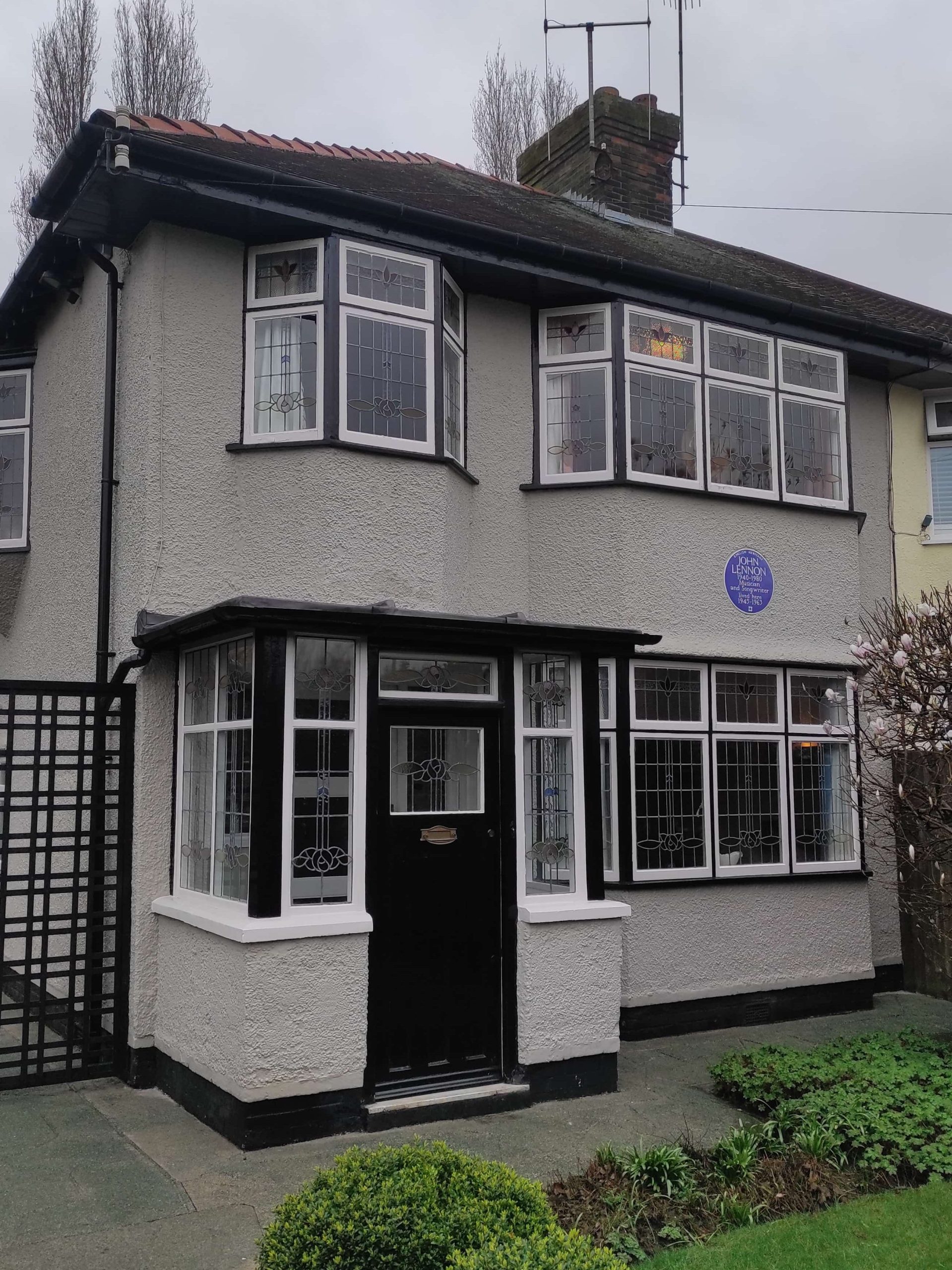 Liverpool et les Beatles : musées, visites, et lieux emblématiques à ne pas manquer 4 mendips, maison d'enfance de john lennon. devanture en crépis grise avec fenetres et porte noires.
