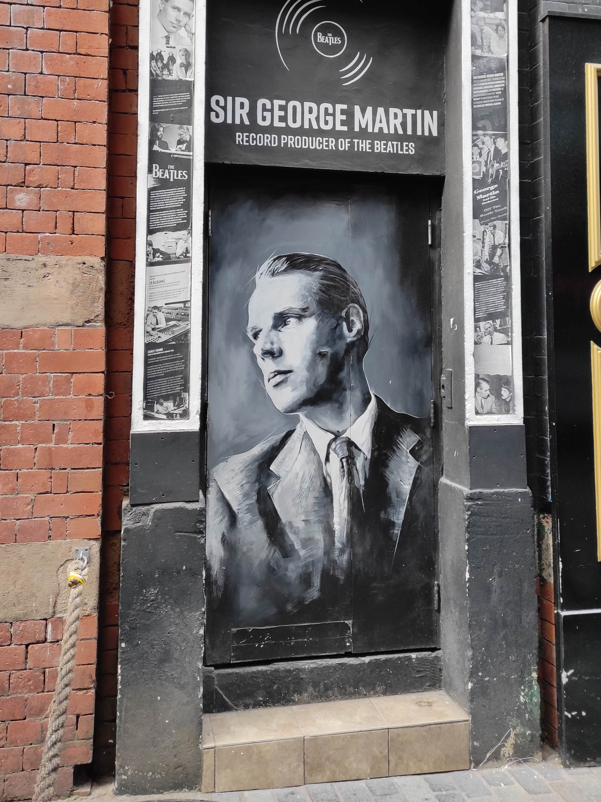 Liverpool et les Beatles : musées, visites, et lieux emblématiques à ne pas manquer 11 Peinture de George Martin le producteur des Beatles en noir et blanc sur les murs de Matthew Street