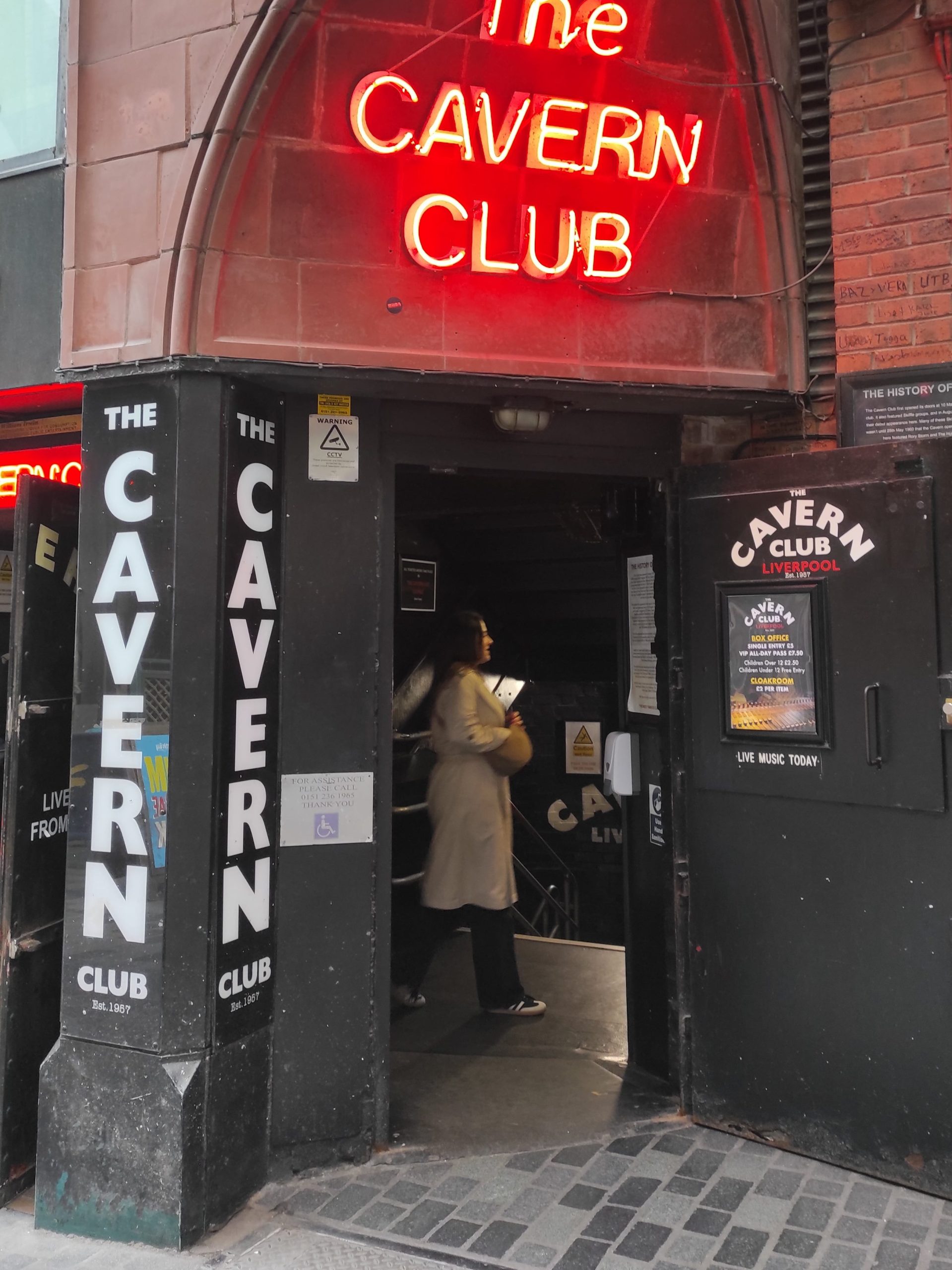 Liverpool et les Beatles : musées, visites, et lieux emblématiques à ne pas manquer 2 entrée du club cavern avec néon rouge du club sur mur en pierre rouge avec porte noire et nom du cavern écrit en blanc