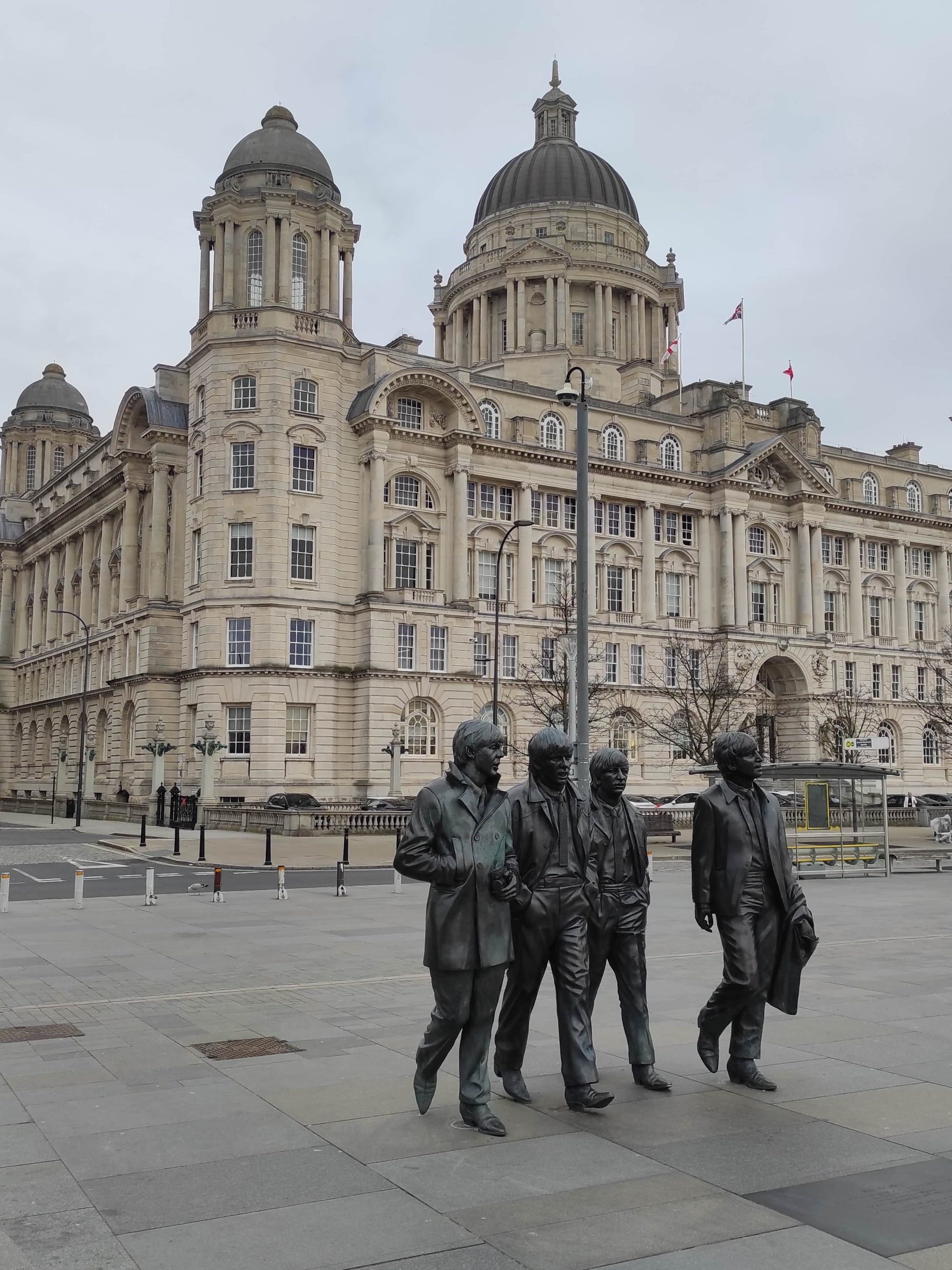 Liverpool et les Beatles : musées, visites, et lieux emblématiques à ne pas manquer 14 Statues des Beatles sur Albert Docks à Liverpool devant bâtiment en pierres blanches