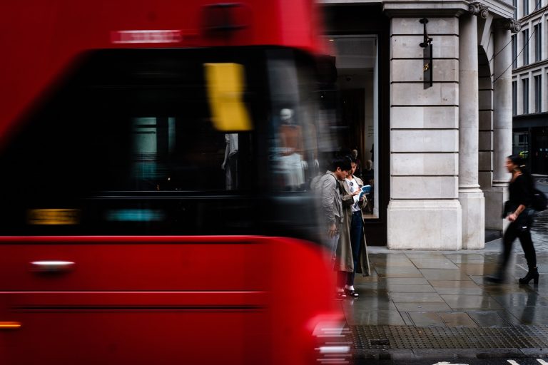 avant de bus rouge anglais au premier plan avec rue de londres en arrière plan avec des gens des marchent sur le trottoir