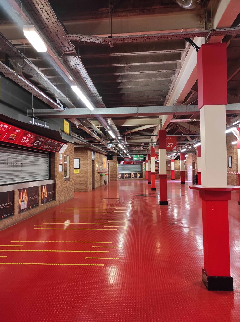 Visiter Old Trafford à Manchester : notre retour d’expérience et conseils pour vous organiser 4 couloirs du stade d'old trafford à Manchester avec sol rouge et stand de nourriture fermé