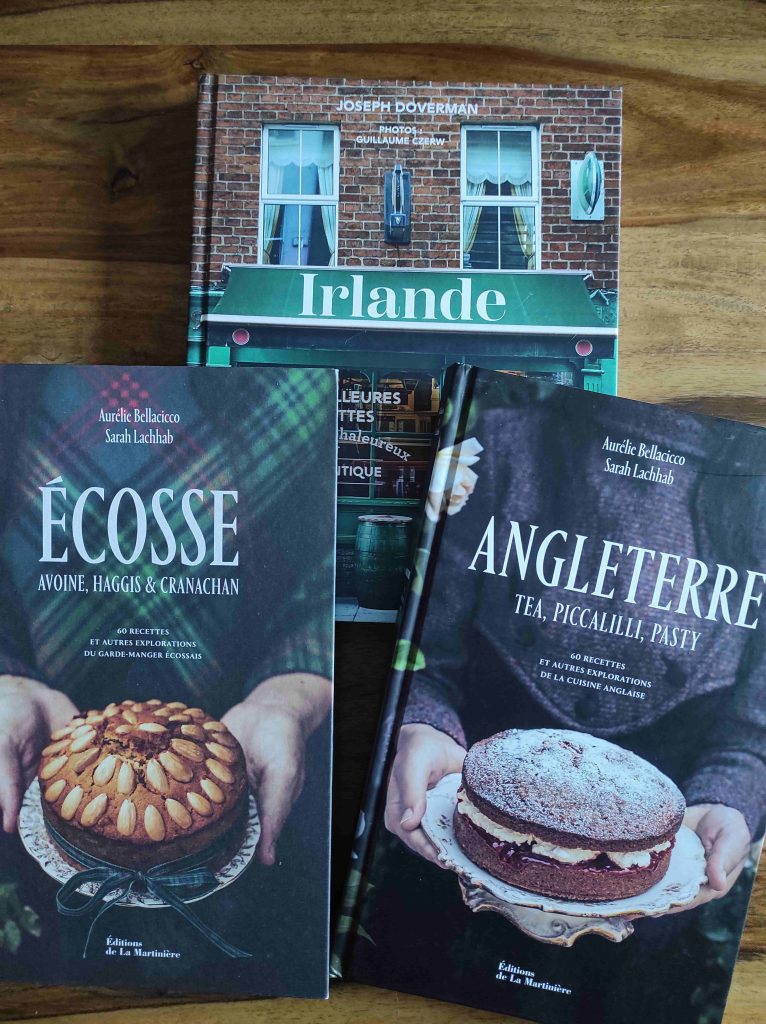 Visiter le Royaume-Uni et l’Irlande : 10 Livres Pour Voyager Depuis Chez Soi 2 trois couvertures de livres de cuisine : un sur l'écosse à gauche avec une photo de gateau et un tartan, un sur l'angleterre à droite avec une photo de gateau, un sur l'irlande derrière avec une photo de pub vert